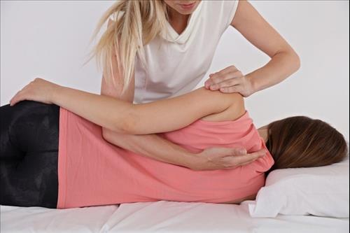 אישה שוכבת עוברת טיפול פיזיותרפיה בגב כחלק מרפואה פיזיקלית ושיקום